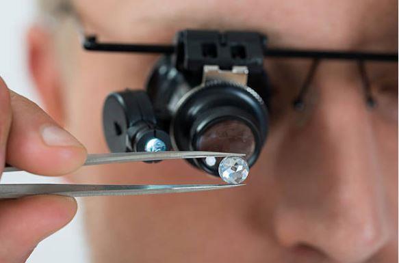 A professional closely examining a diamond's cut and quality